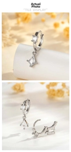 Detail shot of silver earrings with kite-shaped zircon pendants and huggie hoop style