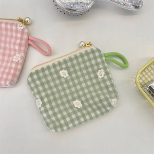 Detail of lace floral embroidery and pearl zipper on plaid canvas coin purse with wrist strap