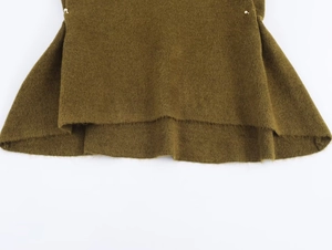 Macro detail of dark green knit top with ruffled hem and small metal rivet accents