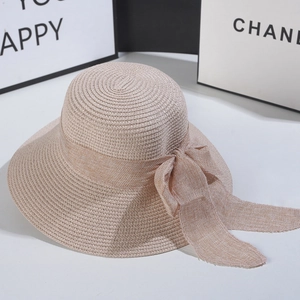 Detail of a wide-brim straw sun hat featuring a large woven bow and spiral texture
