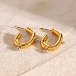 Minimalist gold U-shaped stainless steel earrings with silver beads on a stone surface