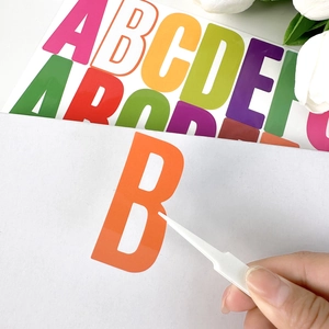 Close-up of colorful waterproof letter stickers with tweezers for easy DIY application