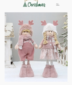 Close-up of pink and white plush Christmas dolls with knit details and festive scene