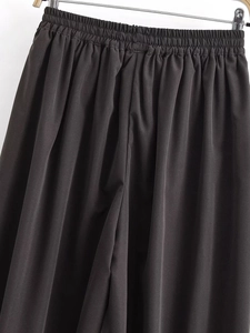 Detailed view of elastic high waistband and pleated fabric on dark casual harem pants