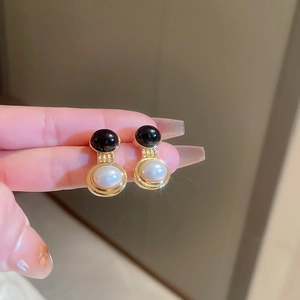 Detail of vintage French style earrings with black beads and white pearls in hand