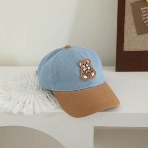 Detailed close-up of bear embroidery and patchwork twill fabric on kids denim baseball cap