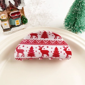Gros plan sur une pince à cheveux blanche avec motifs festifs de rennes et sapins