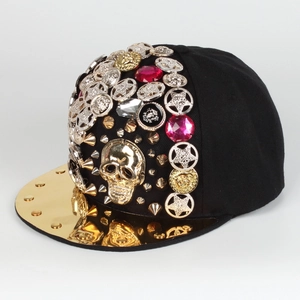 Detail of punk baseball cap featuring gold skull, red rhinestones, and metallic gold brim