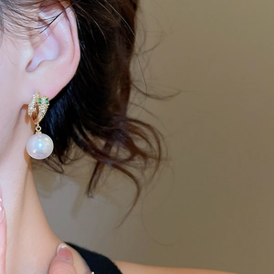 Close-up of 14K gold plated earring featuring a white pearl and green gemstone accents