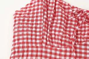Detailed view of red and white gingham fabric with ruffled pleat texture on a spring maxi dress