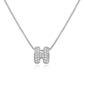 Macro shot of silver letter H pendant with clear crystals on a box chain necklace