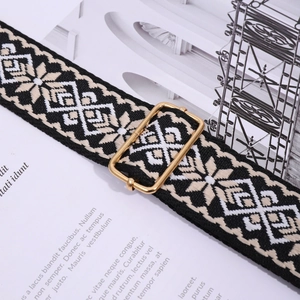 Macro shot of ethnic woven bag strap in black and beige with gold metal buckle