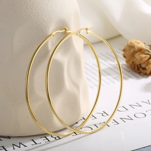 Orecchini a cerchio grandi placcati in oro 18K per donna su sfondo elegante