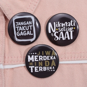 Detailed view of black tinplate badges with inspirational text on pink denim fabric