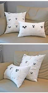 Detail of white ghost throw pillow covers with soft boucle embroidery on a beige sofa