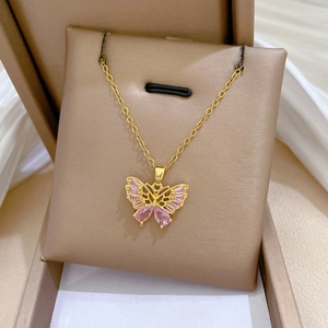 Détail d'un collier papillon doré serti de pierres roses dans son coffret à bijoux