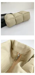Detail of silver metal zipper and quilted stitching on beige padded puffer tote bag