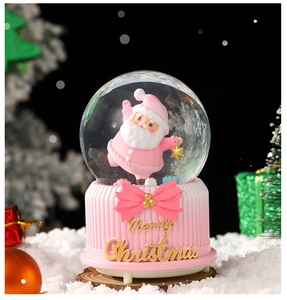 Detail of a pink Christmas snow globe with a Santa figure and gold Merry Christmas base