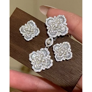Detailed view of clover necklace and earrings set with mother of pearl and pearls