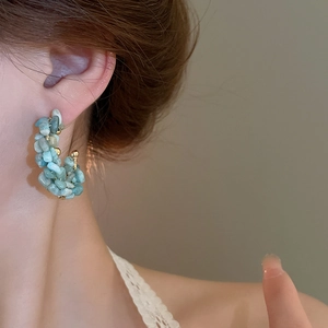 Close-up of C-shaped earrings with sky blue natural stones and gold-toned metal accents