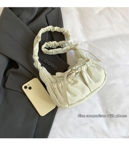 Detail view of beige ruched nylon cloud bag size comparison with a smartphone