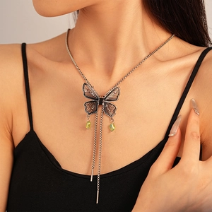 Close-up of gothic butterfly necklace with green crystal drops on a female model