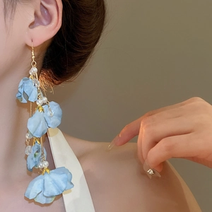 Gros plan de boucles d'oreilles fleurs en tissu bleu avec longs pompons et perles