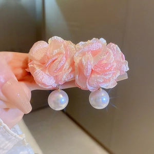 Macro detail of pink fabric flower earrings with elegant white pearl drop pendants