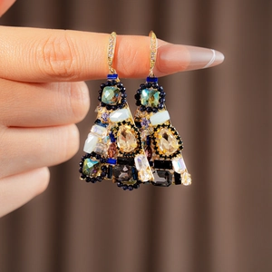 Close-up of bohemian triangle earrings with colorful zircons held by a hand