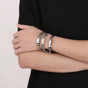 Three men's stainless steel wire cable bracelets in silver and gold on a model's wrist
