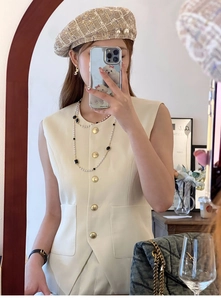 Detailed view of layered pearl necklaces and metal button vest on a female model
