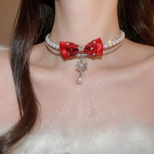 Detail of red bow pearl necklace with diamond snowflake pendant on model