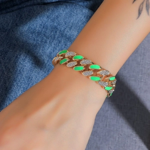 Dettaglio del bracciale Cuban dorato con smalto verde neon e strass su tessuto denim