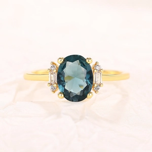 Macro detail of oval blue gemstone ring with gold band and sparkling side stones