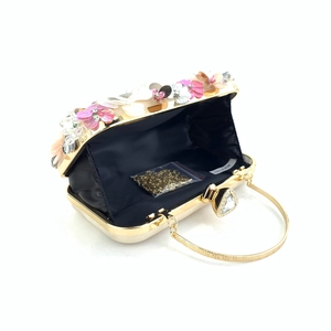 Detail view of the champagne clutch with floral beadwork and a gold heart-shaped crystal clasp