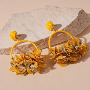 Detail of yellow fabric flower earrings with woven studs on a stone pedestal