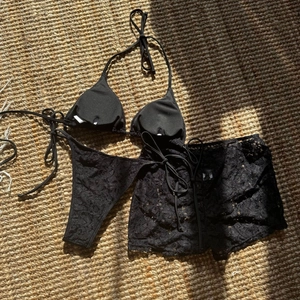 Detailed view of black lace three-piece bikini set including top, bottom and mini skirt