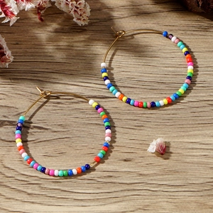 Close-up of bohemian hoop earrings with colorful seed beads on natural wood background