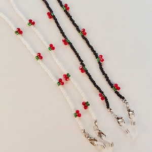 Detailed view of handmade beaded eyewear chains in black and white with cherry charms