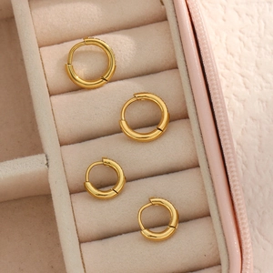 Detail shot of two pairs of gold hoop earrings with zircons on pink leather box