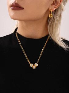Detail of layered gold necklace with colorful beads and white charms on model