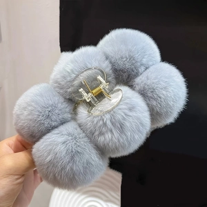Detailed close-up of a large grey-blue plush hair claw clip with soft faux rabbit fur balls