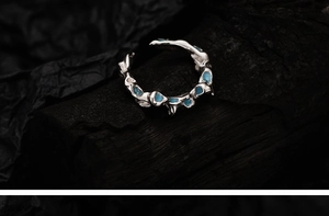 Artistic silver coral ring detail with blue turquoise accents on black charcoal background