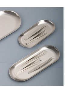 Detail of brushed stainless steel oval trays with assorted precision tweezers set