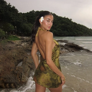 Detail of sexy backless floral halter dress with silky texture and green prints