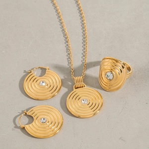 Flat lay of gold titanium steel jewelry set with concentric ripple design and crystals