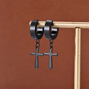 Detail of matte black stainless steel cross earrings hanging on a gold display stand