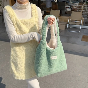 Detail of mint green plush tote bag and light yellow vest with soft winter texture