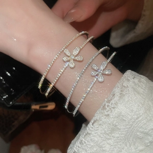 Close-up of four layered zircon flower bangles in gold and silver on a model's wrist