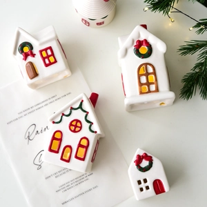Christmas ceramic snow house set with red roofs and festive garlands on white table